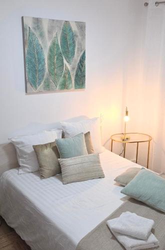 a white bed with pillows and a painting on the wall at Escale 1 Spacieux avec CLIM in Tartas
