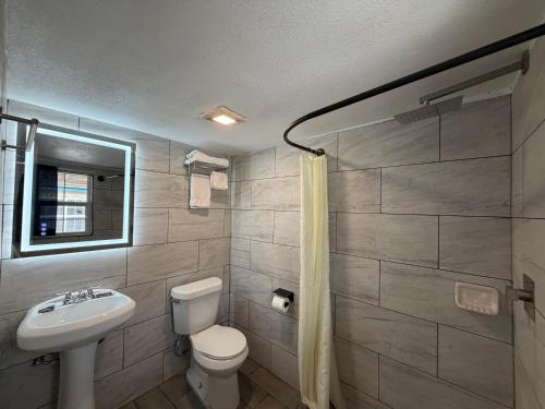 a bathroom with a white toilet and a sink at Ponca Motel in Abilene
