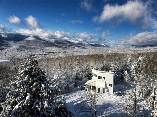 a white house in the snow with a christmas tree at Modern Glass House with Firepit, Views & Private Retreat in Elka Park