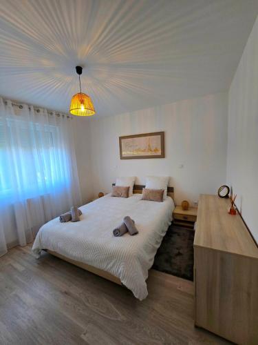 a bedroom with a large bed and a chandelier at DIAG Appartement 3 Chambres in Commequiers