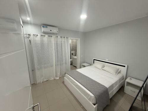 a white bedroom with a bed and a shower at Miles Dreams Laginha in Mindelo