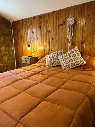 a large bed in a bedroom with wooden walls at Rincón Las Hiedras in Chacras de Coria