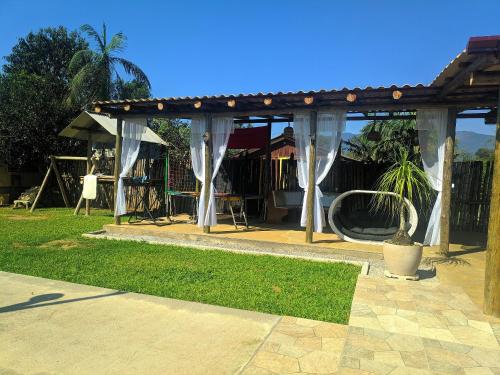 a pavilion with white curtains in a yard at Chácara Caminho do Rio in Morretes
