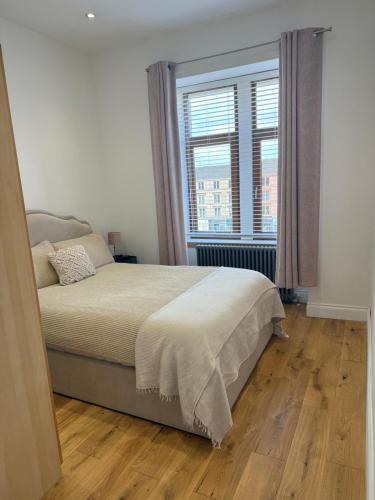a bedroom with a bed and a large window at Top Floor West End Flat - 3-Min Walk to Subway - Park Views in Glasgow