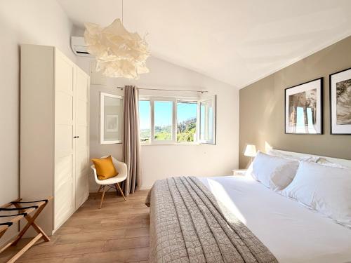 a bedroom with a large white bed and a chair at Villa Vedran in Podgora