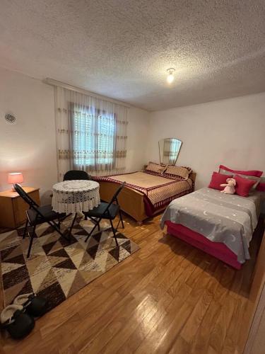 a bedroom with two beds and a table and chairs at Guesthouse Idea in Vusanje