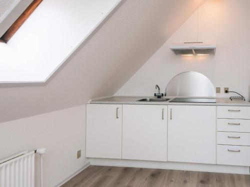 an attic kitchen with white cabinets and a sink at 2 person holiday home in Ringkøbing in Ringkøbing