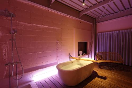 a bathroom with a bath tub and a pink wall at たゆら in Nara