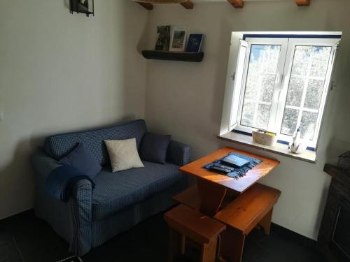 a living room with a blue couch and a table at Casa da Encosta - Piódão in Piódão
