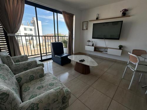 a living room with a couch and a tv at Lindo Departamento con Terraza Vista al Mar in Pimentel