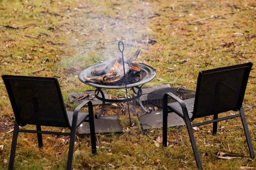 two chairs and a grill with a fire in the grass at The Tiny Chalet by Tiny Away in Bromfleet