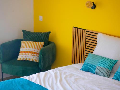 a bedroom with a bed and a green chair at Petite Ancre in Le Gosier
