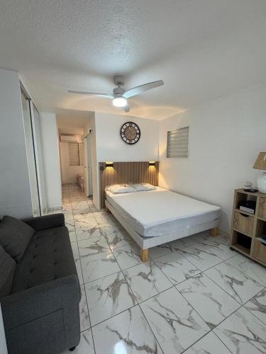 a bedroom with a bed and a clock on the wall at Le Cocon Bleu in Le Moule