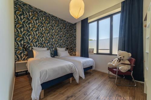 a hotel room with two beds and a teddy bear at Le 10, Reflets dans l'Eau in Saint-Clair-de-la-Tour