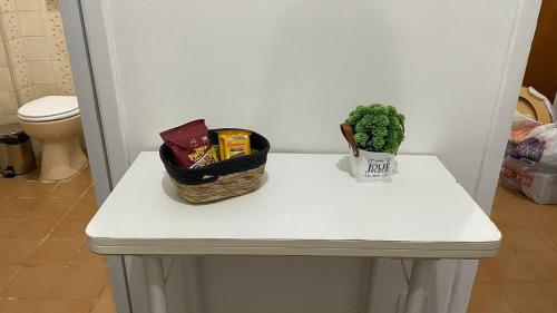 a white table with a plant and a basket on it at Ap Aconchego in Campinas