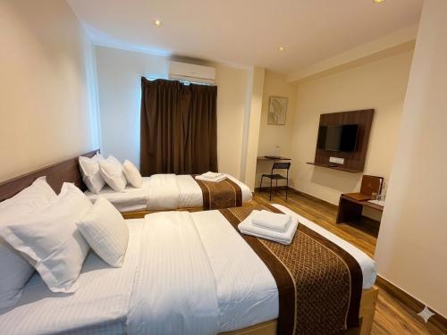 a hotel room with two beds and a television at De Classico Hotel - HBR Layout in Bangalore