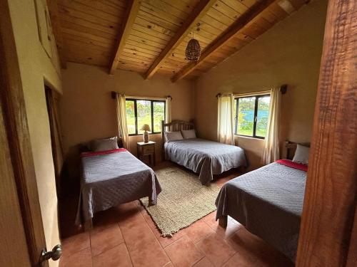 a room with two beds and two windows at Cabaña el nido del monte in Tapalpa