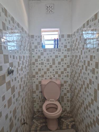 a bathroom with a pink toilet and a window at Maroon House in Narok