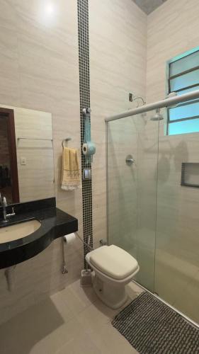 a bathroom with a toilet and a glass shower at Sítio dos Nogueira in Pará de Minas