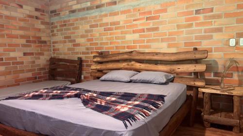 a bedroom with a bed and a brick wall at Sítio dos Nogueira in Pará de Minas