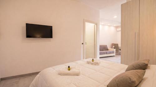 a white bedroom with a bed with towels on it at Dimoras Central Studio 4 Guests Parking in Olbia