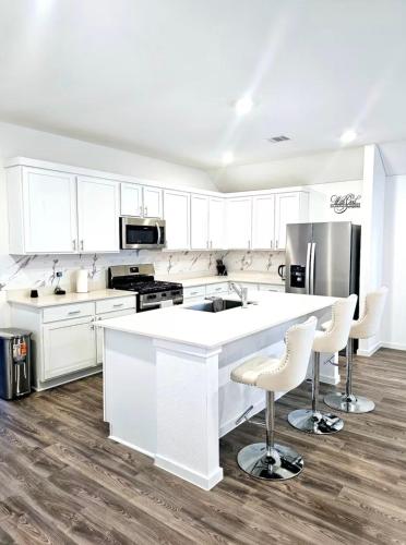 a kitchen with white cabinets and a kitchen island with bar stools at Luxe Haven in Richmond