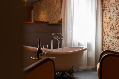 a bath tub with a bottle of champagne next to a window at Spaccavento Boutique Rooms in Chioggia