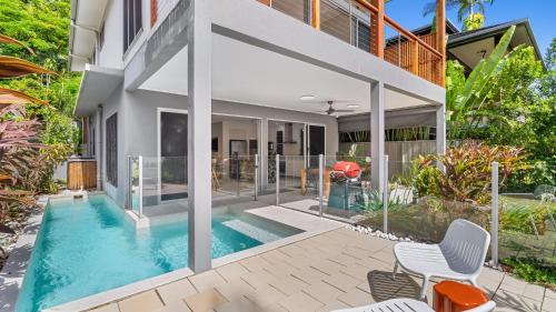 an external view of a house with a swimming pool at Sandveil Absolute Beachfront Access House in Trinity Beach