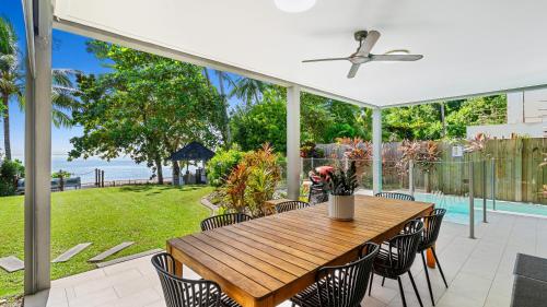 a patio with a wooden table and chairs at Sandveil Absolute Beachfront Access House in Trinity Beach