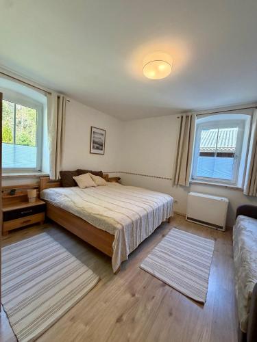 a bedroom with a large bed and two windows at Traunzeit Apartment in Ebensee