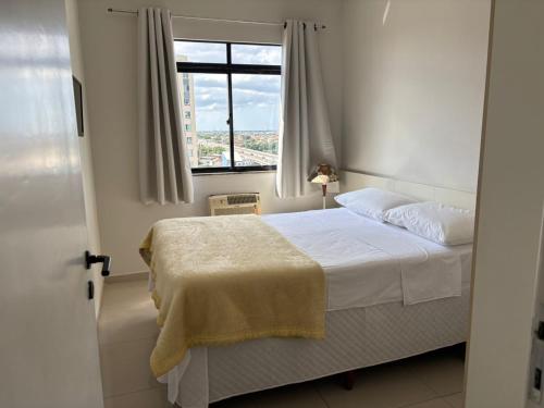 a bedroom with a white bed and a window at Flat Jardim de Allah in Campos dos Goytacazes