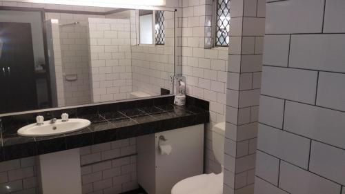 a white bathroom with a toilet and a sink at Tully Motel in Tully