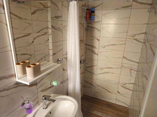 a white bathroom with a shower and a sink at Apartmani PASHA in Nikšić