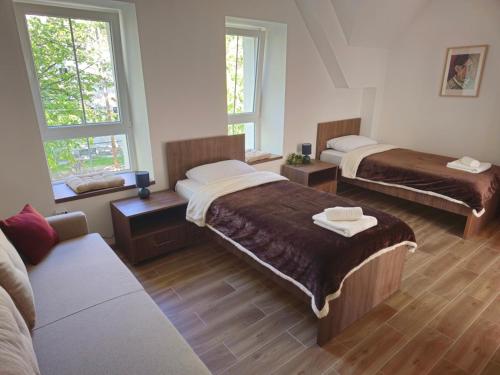a hotel room with two beds and a couch at Apartmani PASHA in Nikšić