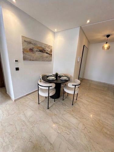 a dining room with a table and chairs and a painting at Diyafa Invest in Oulad Akkou