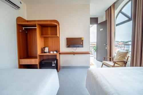 a hotel room with two beds and a tv at Cát Boutique Hotel in Dong Hoi