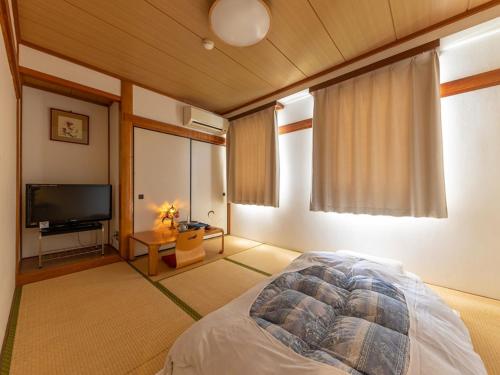 a bedroom with a bed and a flat screen tv at Business Hotel Hayashiso in Miyazaki