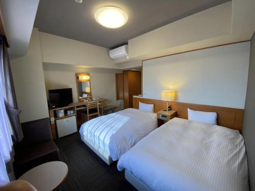 a hotel room with two beds and a television at Hotel Route-Inn Mooka in Mooka