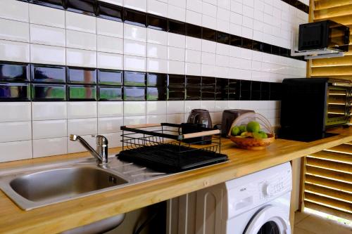 a kitchen counter with a sink and a dish drying rack at Bungalow confortable et calme sud de la Martinique in Rivière-Salée