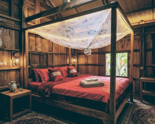 a bedroom with a canopy bed in a room with wooden walls at Family Batcave Homestay in Battambang