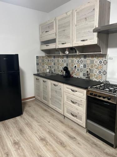 a kitchen with white cabinets and a black refrigerator at Avram Iancu 365 in Floreşti