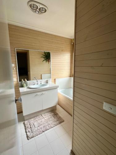 a bathroom with a sink and a tub and a mirror at Hannahs Haven in Traralgon