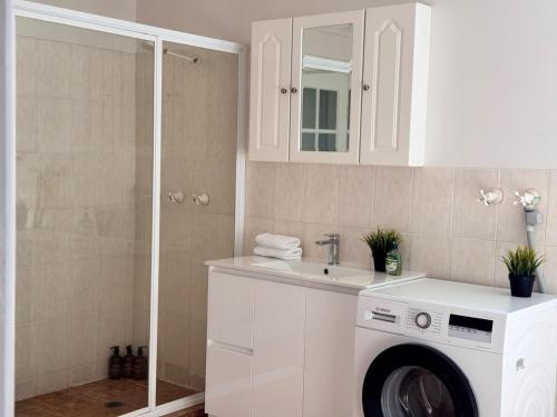 a bathroom with a washing machine and a sink at Pine Cabin Right A Short Stroll to Zig Zag Railway in Clarence