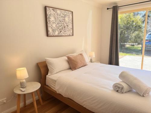 a bedroom with a large bed with a window at Pine Cabin Right A Short Stroll to Zig Zag Railway in Clarence