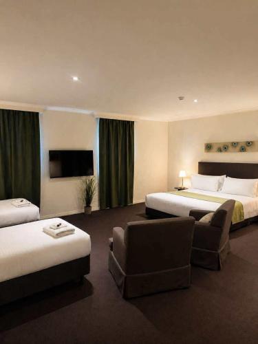 a hotel room with two beds and a couch at The Richmond Hotel - Adelaide in Adelaide