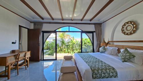a bedroom with a bed and a desk and a window at Casa Anagata Pandawa in Ungasan