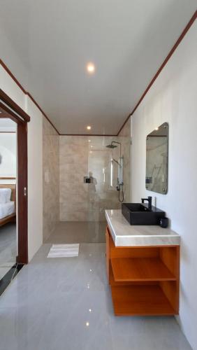 a bathroom with a sink and a shower with a mirror at Casa Anagata Pandawa in Ungasan