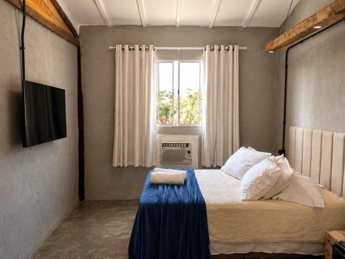 a bedroom with a large bed with a window at Refúgio Pauapique - Suítes com café da manhã, ar condicionado e frigobar à 900 metros da Rota do Vinho in São Roque