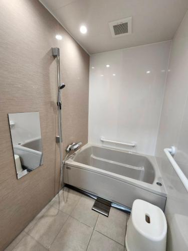 a bathroom with a bath tub and a toilet at Guesthouse Face to Face in Fujinomiya
