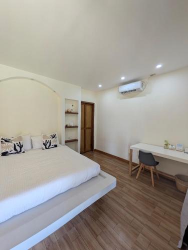 a white bedroom with a bed and a desk at Cozy Shell in General Luna